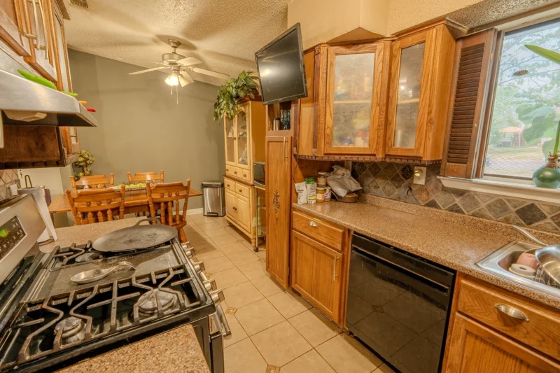 Kitchen with wooden cabinetry, a gas range, and a window overlooking greenery